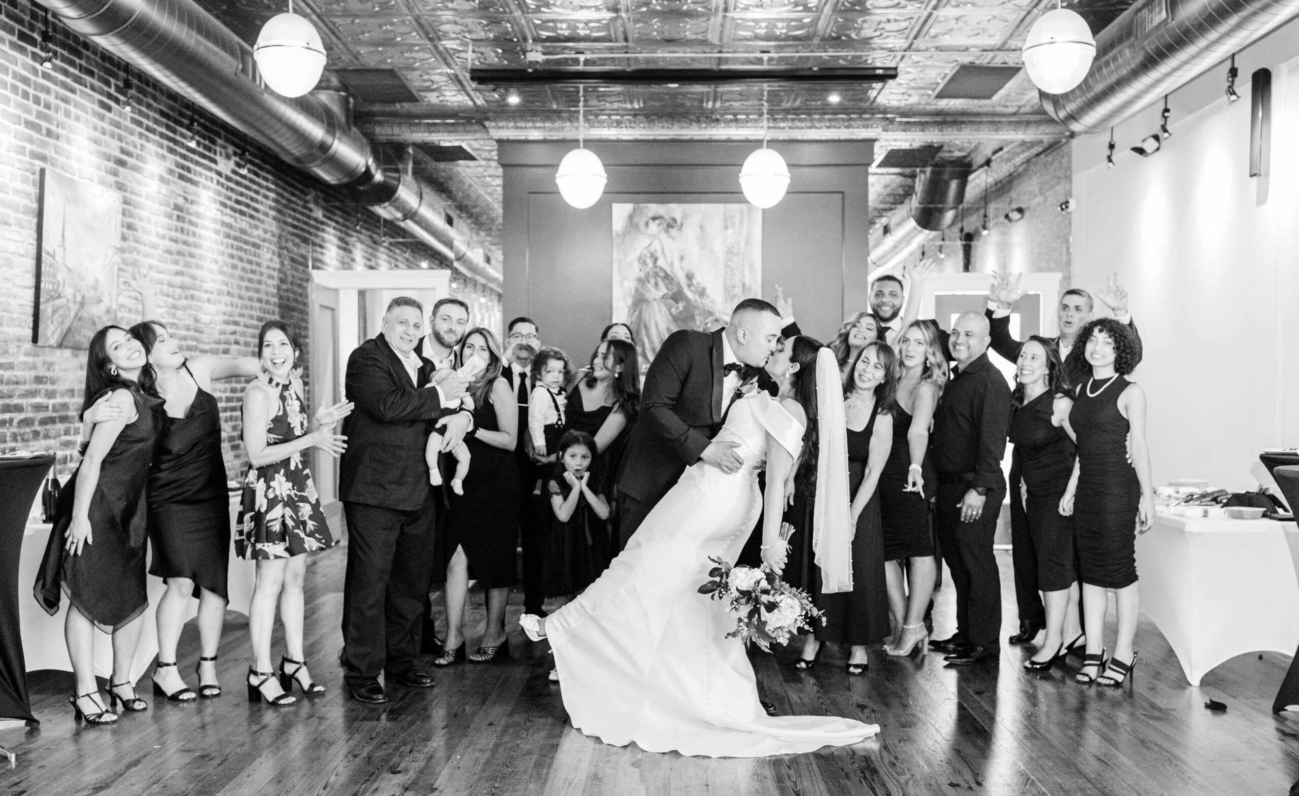 Groom dips bride and everyone celebrates a wedding at the 718 Venue in Fredericksburg, Virginia. Taken by Bethany Aubre Photography.